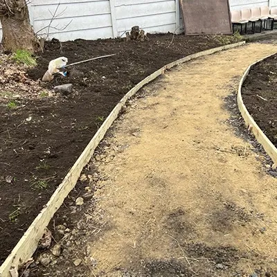 a garden path in a yard with a tree in the background
